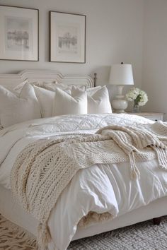 a white bed sitting in a bedroom next to two pictures