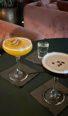 two cocktails sitting on top of a table next to each other in front of a couch