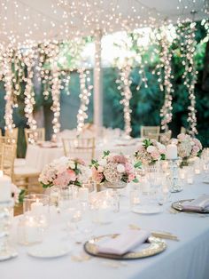 the table is set with white and pink flowers, candles, and napkins on it