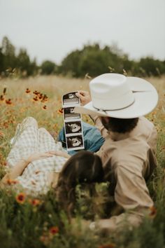 a man and woman laying in the grass with an old cell phone on their lap