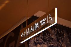 a street sign hanging from the ceiling in front of a wall with writing on it