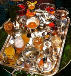 a tray filled with different types of glasses on top of a green tableclothed surface