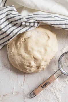 a ball of bread sitting on top of a table next to a measuring spoon and towel