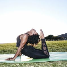 a woman is doing yoga in the grass