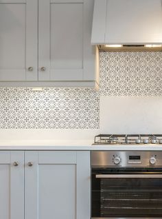 a stove top oven sitting inside of a kitchen next to white cupboards and drawers