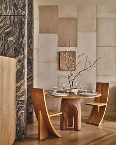 a dining room table and chairs in front of a wall with art work on it