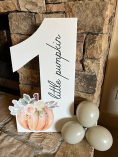 a table with balloons and a number one sign on top of it next to a brick fireplace