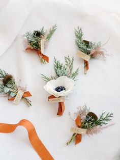 flowers and ribbons are laid out on a white sheet with an orange ribbon around them