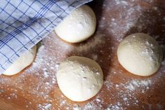 four doughnuts sitting on top of a wooden table covered in powdered sugar