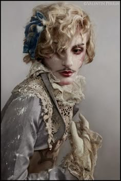 a woman with white makeup and curly hair is dressed in an old - fashioned costume