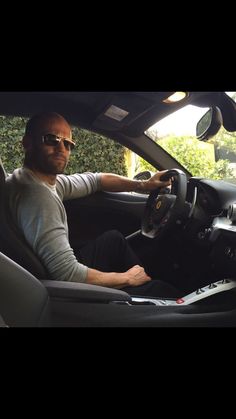 a man sitting in the driver's seat of a car with his hands on the steering wheel