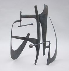 a metal sculpture on a white surface with an abstract design in the center and two poles sticking out of it