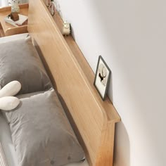 a bed with two pillows on top of it next to a night stand and mirror