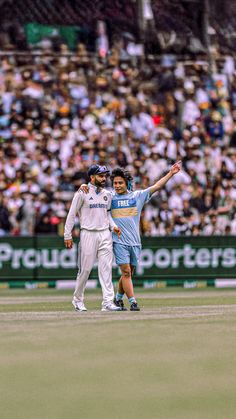 two men standing on top of a field next to each other in front of a crowd