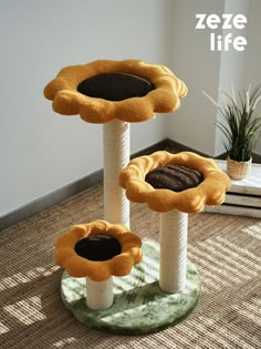 three cat trees with two cats in them on the floor and one has a plant growing out of it