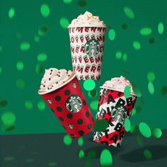 three starbucks cups are sitting on a table with confetti around them and green lights in the background