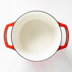 an empty red and white bowl on a white surface