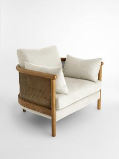 a white couch with two pillows on it's back and armrests, sitting against a wall