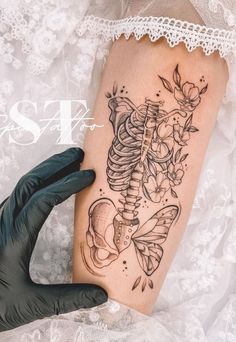 a woman's arm with a skeleton and flowers tattoo on it, next to a glove