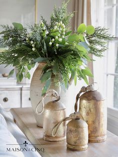 a vase with flowers and greenery sitting on a table