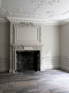 an empty living room with a fireplace and white walls