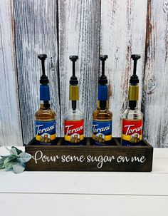 three bottles of soap sitting on top of a wooden tray