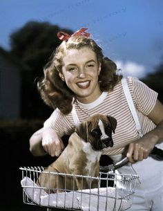 a woman sitting in a basket with a dog