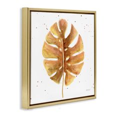 a painting of a large leaf on a white wall with gold trim around the edges