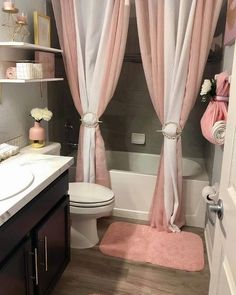 a bathroom decorated in pink and white with lots of curtains on the shower curtain rod