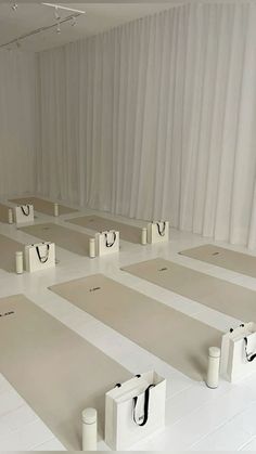 yoga mats lined up on the floor in front of white drapes with black handles