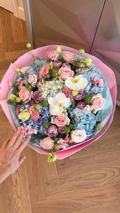 a bouquet of flowers sitting on top of a wooden floor next to a person's hand