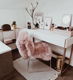 a pink chair sitting in front of a desk with a mirror and pictures on it