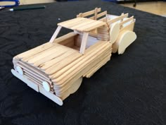 a toy truck made out of wood sitting on top of a black cloth covered floor