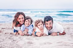 a family laying in the sand at the beach