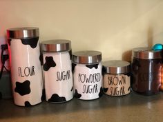 the kitchen canisters are decorated with black and white cow print, which reads flour, sugar, brown sugar