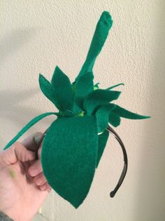 a hand holding a green hat with leaves on it