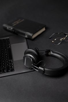 an open laptop computer sitting on top of a desk next to headphones and glasses