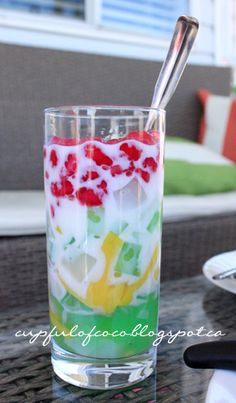 a glass filled with liquid sitting on top of a table next to a chair and window