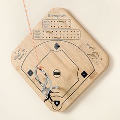 a wooden baseball game board with scissors and string attached to it, on a white background