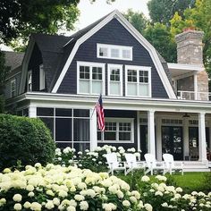 a black and white house with flowers in the front yard