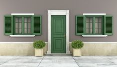 a green door and window in front of a gray building with two planters on the sidewalk