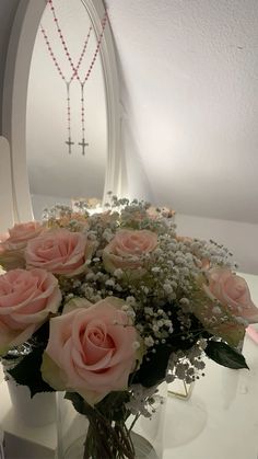 a vase filled with pink roses and baby's breath in front of a mirror