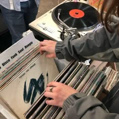 a person holding a record player in front of a bunch of records on a table