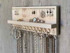 a wall mounted jewelry rack with several pairs of earrings hanging from it's sides