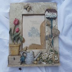 an old photo frame is decorated with flowers and gardening items