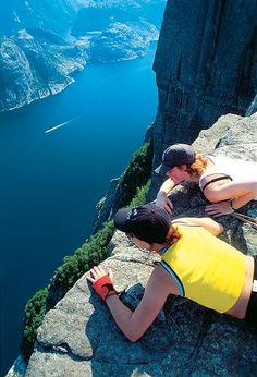 two people sitting on the edge of a cliff