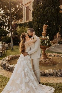 a bride and groom are standing in front of a fountain at their wedding reception outside