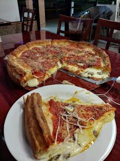 two pizzas sitting on top of a table with one slice missing from the pie