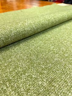 a close up view of a green fabric on a wooden table with other items in the background