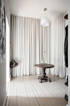 a room with white walls and wooden flooring has a round table in the center